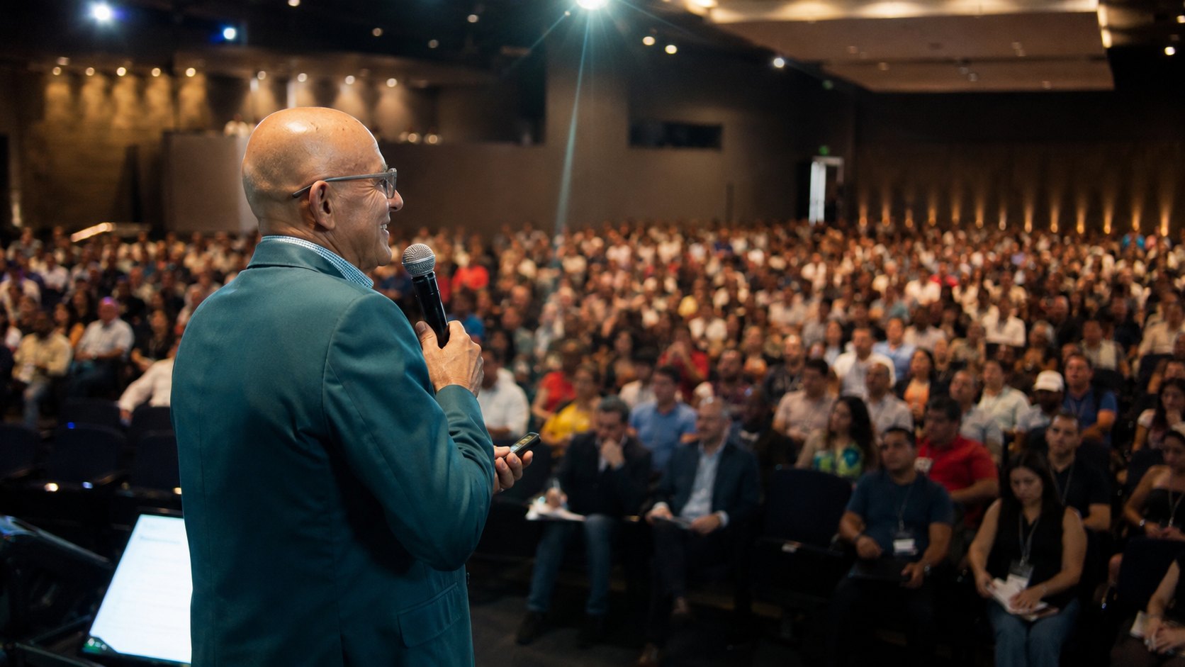 Astênio Araújo em palestra, de microfone na mão, diante de um auditório lotado